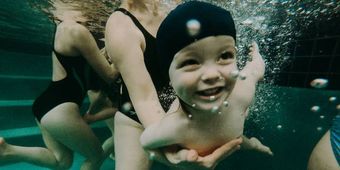 Bébé sous l'eau qui sourit.